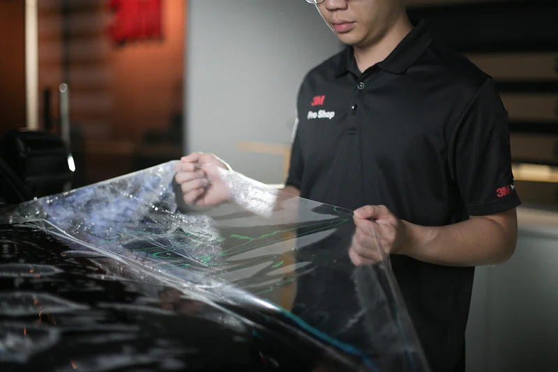 A 3M technician prepares a clear PPF sheet before installation on a car.