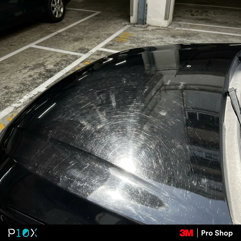 New car swirl marks visible under direct sunlight on a black bonnet at a Bandar Sunway condo carpark