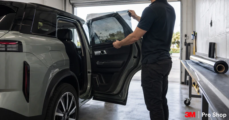 Jaecoo J7 window tint being checked against a rear door pane before fitting in a professional film bay.